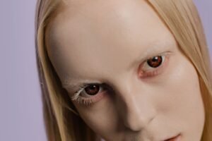 Close-up photo of a woman with striking contact lenses and blonde hair.