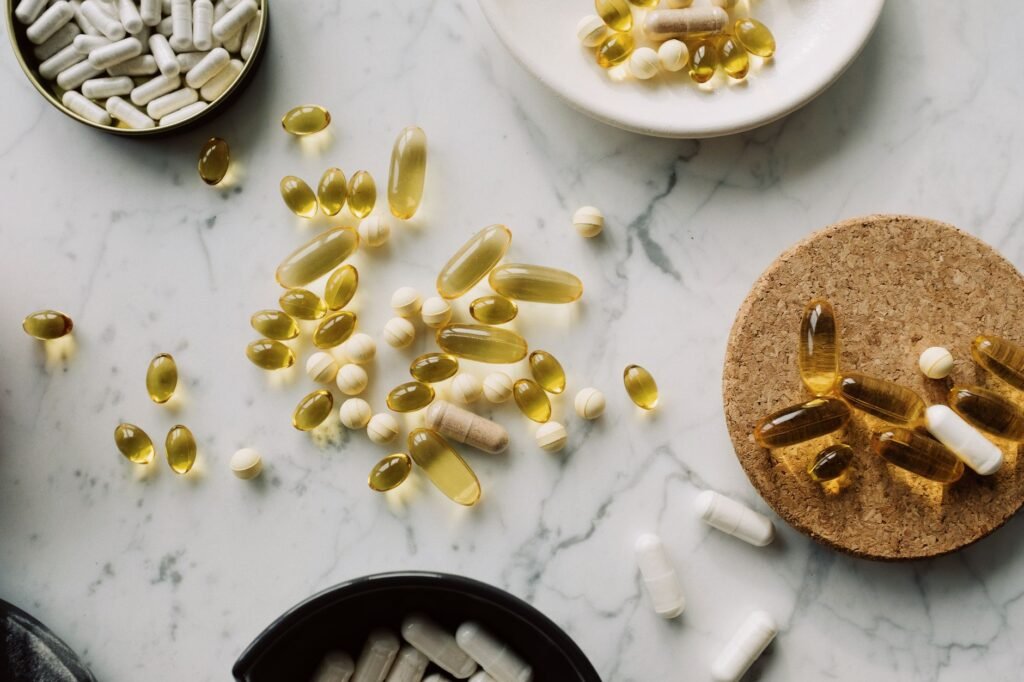 Health supplements and vitamins in gelatin capsules arranged in various container on marble surface